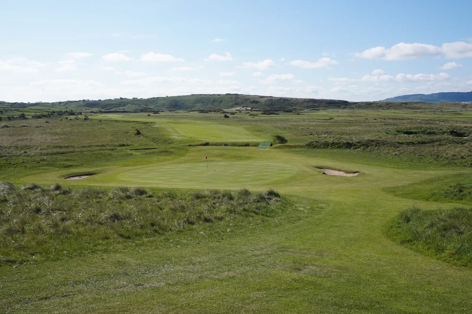Elevated view of a golf green with bunkers and rolling hills